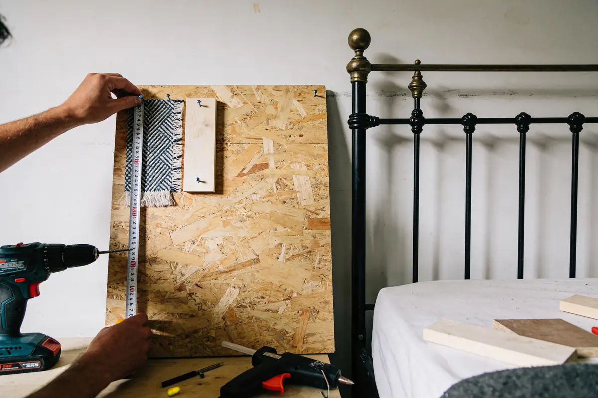 Planche en bois avec échantillon de tissu mesuré, perceuse, lit en fer forgé. Atelier bricolage.