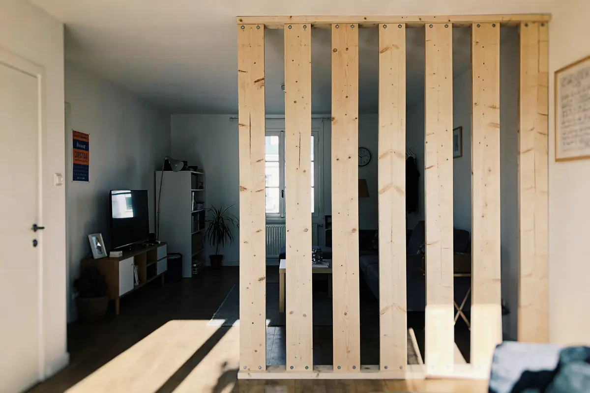 Séparation intérieure en bois dans un salon lumineux avec télévision et meubles modernes.